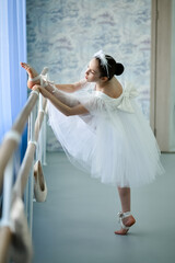 A beautiful girl ballerina in a white dress is engaged at the stonk. She's in a dance studio....