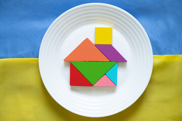 The yellow-blue national flag of Ukraine as a background and a children's house made of cubes lies...