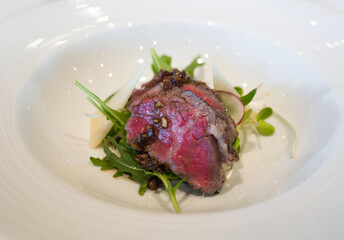 Slow cooked mini beef short ribs served on white plate. Sunday brunch main course dining.