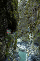 Steep and tall rock faces, deep gorge, river and small road dug on the edge of rock at Swallow Grotto (Yanzikou) at the Taroko National Park in Taiwan.