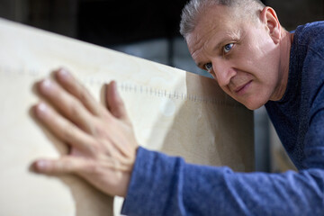 Mature carpenter checks the quality of the plywood frame. Inspection and quality control of the...