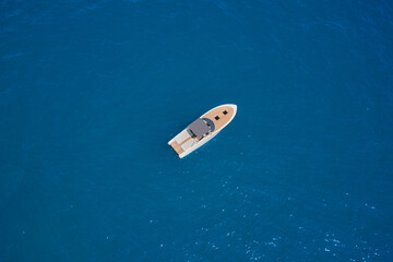 Modern boat with wooden trim top view. Boat with a gray awning in the parking lot aerial view. One boat on blue water drone view.