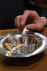 たばこの灰を落とす手のクローズアップ