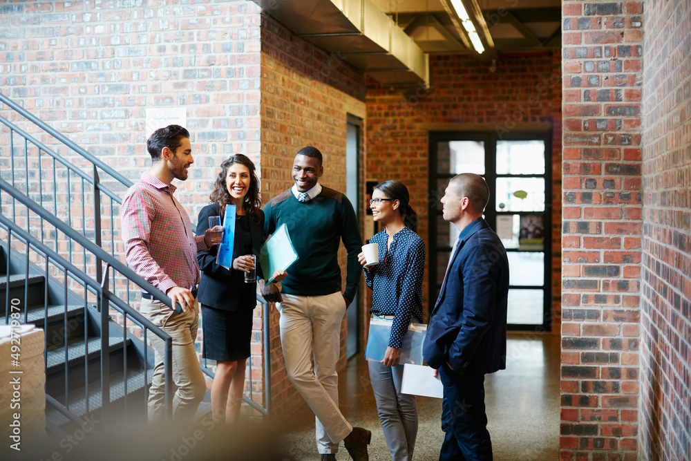 Poster action is key to all success. shot of a group of businesspeople having a discussion in the hallway.