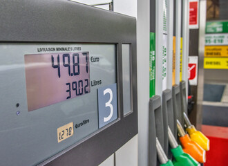 Gas prices at a petrol pump in a petrol station. Close up on fuel nozzle with green, orange and...