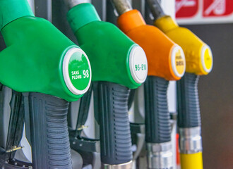 Detail of a petrol pump in a petrol station. Close up on fuel nozzle with green, orange and yellow colors in oil dispenser with gasoline and diesel in service gas station.