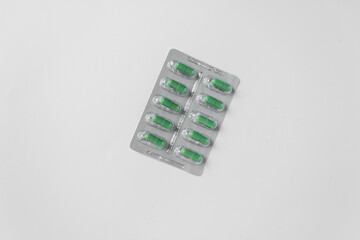 Silver blister with supplements and vitamins in green capsules on white background. Health care...