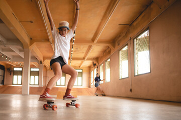 skater woman person playing skateboard in sport gym, young Asian woman are happy and fun with skateboarding lifestyle in city, teenage hipster female trendy fashion © chokniti