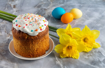 Easter cake, eggs and daffodil flowers on kitchen table.