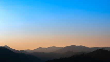 Fototapeta na wymiar Mountains Alternate behind The Blue and Yellow Sky
