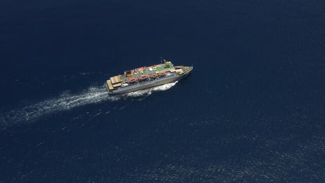 Ship cruising open water. Aerial top view of smart cargo ship carrying container and running fast for export cargo from container yard port to custom. Contrail line in ocean by large ship very fast.