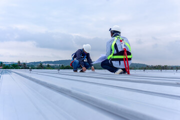 Two engineers wearing full safety body harness working inspection on roof top - obrazy, fototapety, plakaty