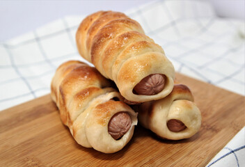 Sausages in dough on a wooden board. Sweet pastry. Fast food.