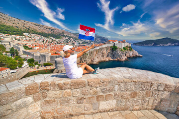 Girl with Croatian flag on Dubrovnik walls of Croatia from Fort Lovrijenac fortress in West Harbour with Fort Bokar. Dubrovnik UNESCO World Heritage Site is an old Venetian city of Croatia in Dalmatia