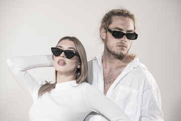 Couple in fashion black sunglasses. Young couple posing with sunglasses. Studio shot on gray background.