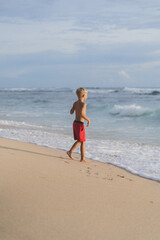 A child on the beach plays in the waves of the ocean. Boy on the ocean, happy childhood. tropical life.