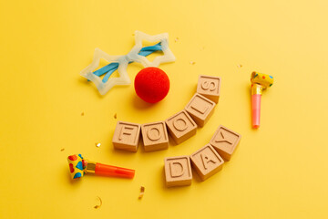 Creative minimalistic concept for April Fools' Day. wooden letters Fools day and festive decor on the yellow background