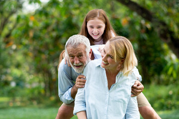 Fototapeta premium happy family elderly caucasian and child caucasian sitting on lawn relax in weekend holiday lifestyle in park .