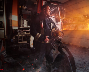 Fototapeta na wymiar Brave fireman posing around fire truck indoors fire station