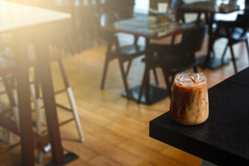 Ice coffee on a black table with cream being poured into it showing the texture and refreshing look of the drink