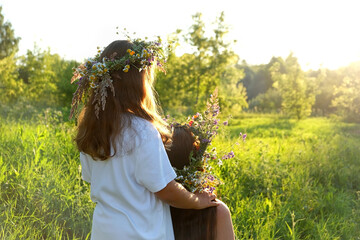 Two girls in flower wreaths on meadow, sunny green natural background. Floral crown, symbol of summer solstice. Slavic ceremony on Midsummer, wiccan Litha sabbat. pagan holiday Ivan Kupala - obrazy, fototapety, plakaty