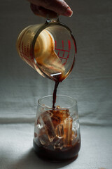 Ice coffee on a white background with cream being poured into it showing the texture and refreshing look of the drink