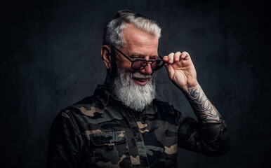 Joyful old man with tattoos dressed in camouflage clothing