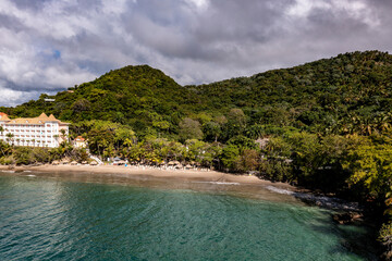 a tropical island with a white sandy beach and a house with a red roof and a turquoise sea in the Dominican Republic taken from a drone 