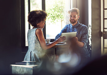 They come here for the fast internet and friendly service. Shot of two people using a digital...