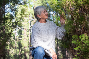 Portrait of carefree caucasian white-haired senior woman in the woods excursion. Smiling mature elderly people enjoying nature, care of environment, freedom vacation travel in the forest