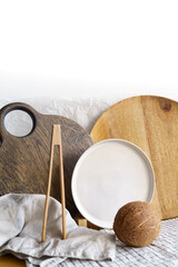 Plates and wooden boards, wooden tweezers, napkins and other kitchen staff and coconut in natural light