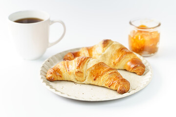 home backed fresh French croissants with orange jam and cup of black coffee isolated on white background