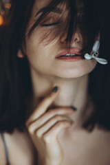 Obraz premium Portrait of a woman with a flower. A beautiful girl holds a snowdrop flower near her face. High quality photo