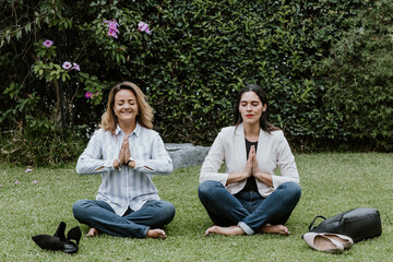 Latin business women sitting on grass and meditating at terrace office in Mexico Latin America	
