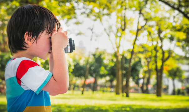 little kids boy taking a picture using a vintage retro film in nature park