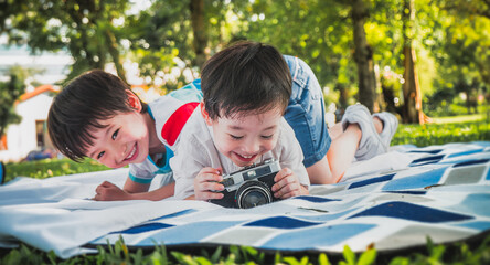 little kids boy enjoying learning professional photographer taking a picture using a vintage retro film in nature park ,People lifestyle concept.