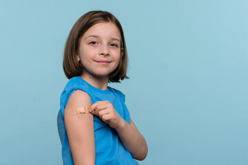 Child Vaccinated. Cute Little Girl pointing finger at adhesive plaster bandage on her arm after...