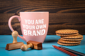 You Are Your Own Brand. Coffee mug with text on office desk