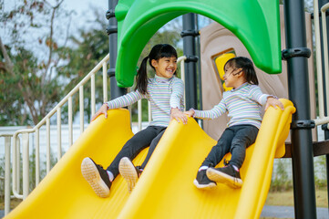 Two girls play slides in the playground.