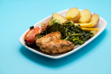 Grilled caviar cod fish with greens and fresh lemon on white small plate.