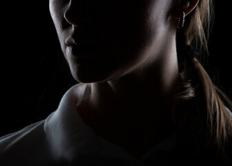 Close-up part of face silhouette with lips and neck of young woman. Isolated on black background