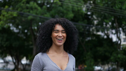 A happy Brazilian woman standing outside in urban street