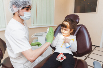 dentist and little girl give each other five. Doctor and child. Successful work of a dentist. Dental modern clinic.