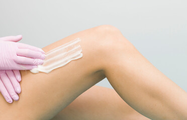 Fototapeta premium Hair removal in a luxury spa studio. Wax for women's feet with saccharin. Hot sugar. The product is made of a wax bowl. The bank's salon.