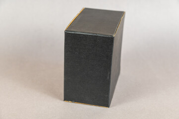 Rectangular black box on a gray background. Closed cardboard package with correct geometric shape.