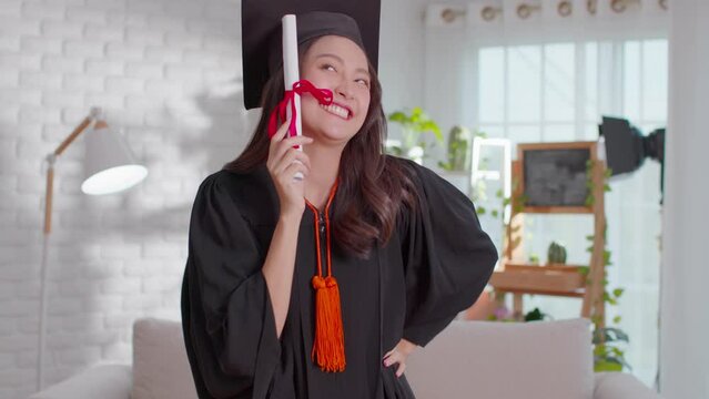 An Asian girl is greetings on her graduation ceremony. She is extremely happy on her successful and  achievement moment. She is so lively on her gown and obviously cheerful.