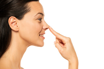 young happy woman touches her nose with her finger on a white background