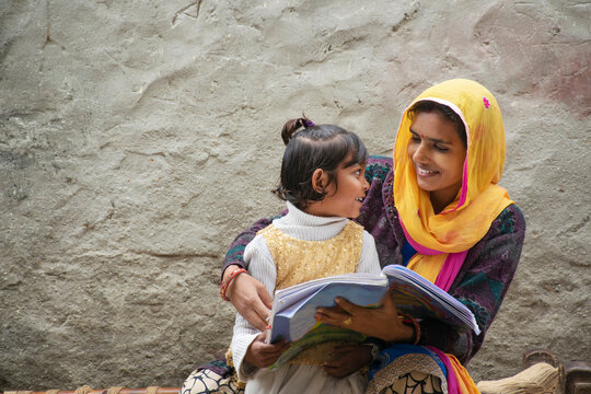 happy indian mother and daughter, mother helping her daughter in study