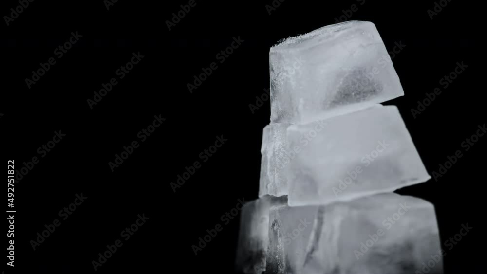 Poster square ice cubes are spinning on a black background. water freezing in square shape. wet ice rotates