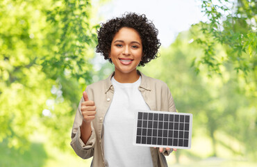 sustainable energy, power and sustainability concept - happy smiling woman with solar battery model...